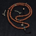 Handcrafted Nepali bodhi seed mala with phoenix eye beads, brass accents, and skull details