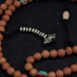 Handcrafted Nepali bodhi seed mala with phoenix eye beads, brass accents, and skull details