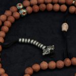 Handcrafted Nepali bodhi seed mala with phoenix eye beads, brass accents, and skull details