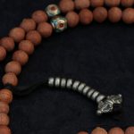 Handcrafted Nepali bodhi seed mala with phoenix eye beads, brass accents, and skull details