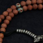 Handcrafted Nepali bodhi seed mala with phoenix eye beads, brass accents, and skull details
